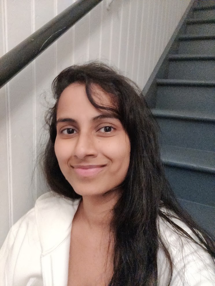 Ruhi smiling in a white hoodie